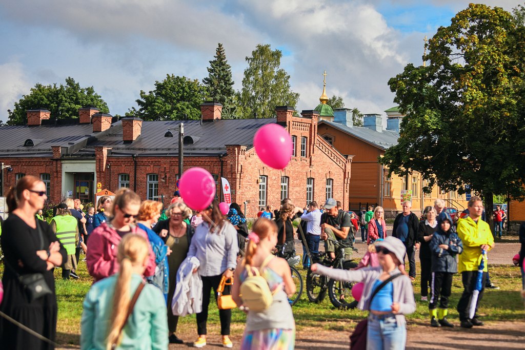 People with pink balloons standing outdoors in sunny weather